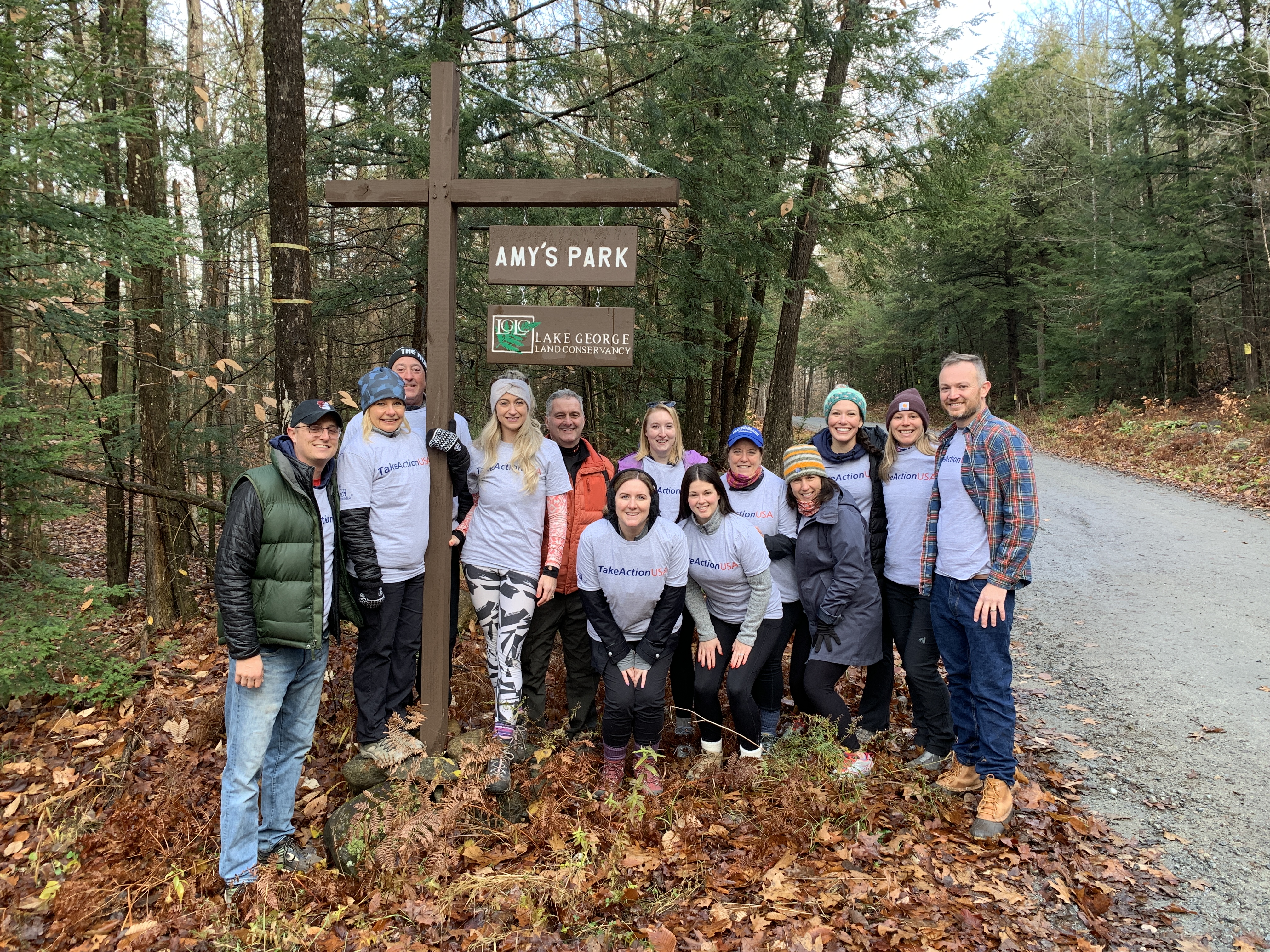 Group of 12 men and women stand in front of the Amy's Park sign. They are employees of Novo Nordisk, and volunteered for the day at Amy's Park on November 15.